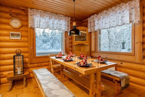 a dining room with a table and two windows at Villa Äkäsjoensuu in Äkäslompolo