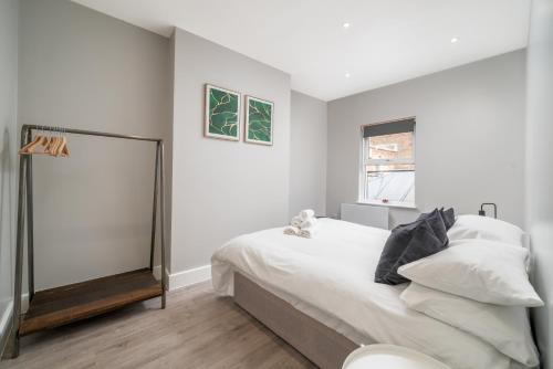 a bedroom with a bed with white sheets and a window at Luxury Flat with private terrace in the Heart of Kingston in London