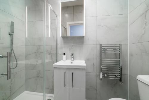 a white bathroom with a sink and a shower at Luxury Flat with private terrace in the Heart of Kingston in London