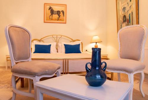 a bedroom with a bed with chairs and a vase on a table at Dar Yessine Boutique Hôtel in Sousse