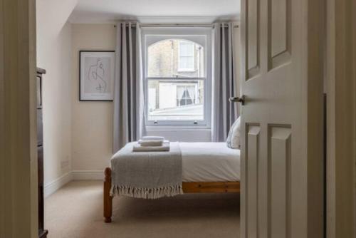een slaapkamer met een bed en een raam bij The West Kensington Collection in Londen