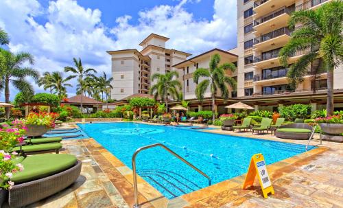 a pool at a resort with chairs and a building at Ko Olina Beach Villas O1004 in Kapolei