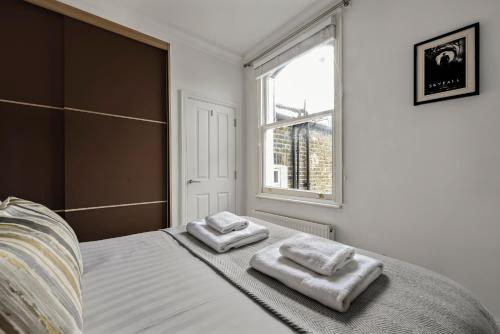 1 dormitorio con 1 cama con 2 toallas en The West Kensington Collection, en Londres