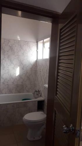 a bathroom with a toilet and a tub and a window at Gifted Apartment & Residence in Abuja