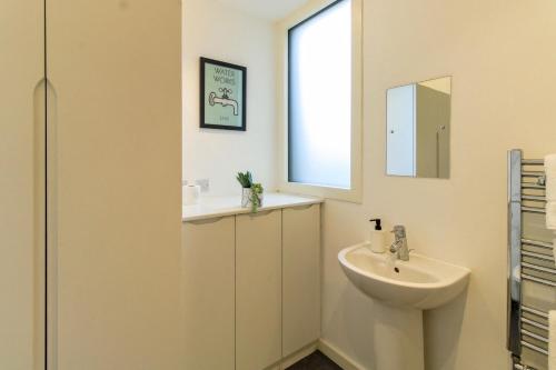 a white bathroom with a sink and a mirror at 4 Bed MK Cosy & Well equipped House in Shenley Church End