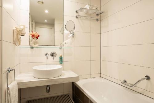 a white bathroom with a sink and a tub at B-aparthotel Grand Place in Brussels