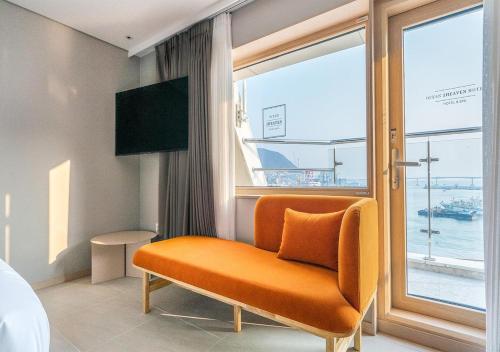 una silla naranja en una habitación de hotel con ventana en Nampo Ocean2Heaven Hotel& Spa en Busan