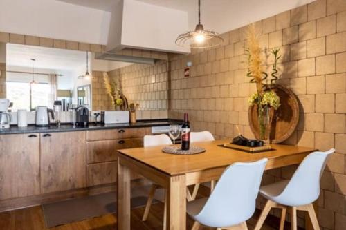 a kitchen with a wooden table and white chairs at Apartamento Bela Vista Leni in Poço Partido