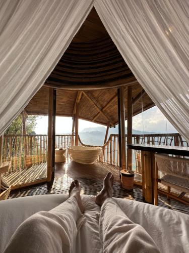 a person laying on a bed in a tent at 3 Bdr - Luxury Cliffside Bamboo Villa in Bungbungan