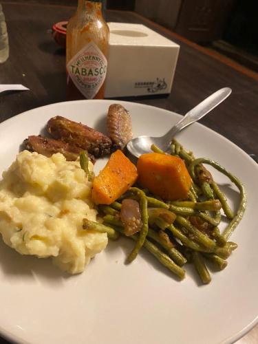 a plate of food with meat mashed potatoes and green beans at The Nest Guest House in Changunarayan