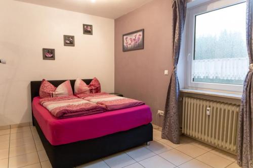Schlafzimmer mit einem Bett mit rosa Bettwäsche und einem Fenster in der Unterkunft NEU! Reiterhof Finkenmühle Fewo Gipsy in Weißenstadt