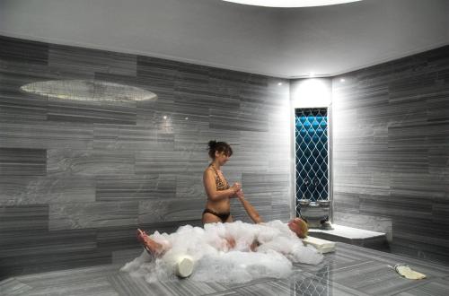 a woman in a bathing suit standing next to a woman laying in a bath room at Batıhan Beach Resort & Spa in Kuşadası