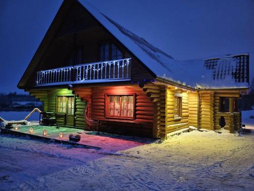 a log cabin in the snow at night at Meijas Nams in Kalupe
