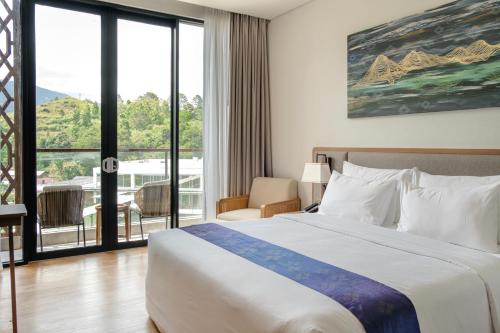 a hotel room with a bed and a large window at Marianna Resort And Convention Tuktuk - Samosir, Marclan Collection in Tuk Tuk