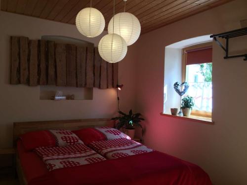a bedroom with a bed with red sheets and lights at Jörgs Ferienwohnung Lohmen in Lohmen
