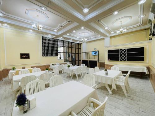 uma sala de jantar com mesas brancas e cadeiras brancas em Green Hotel em Tashkent