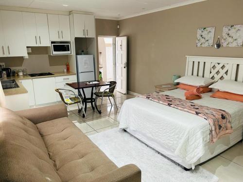 a bedroom with a bed and a kitchen with a couch at Hidden Bliss Guesthouse in East London