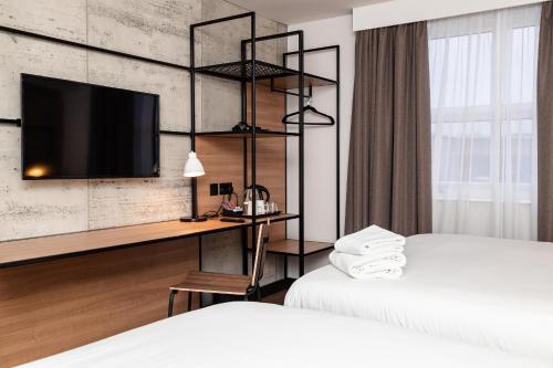 a hotel room with two beds and a desk with a tv at ibis Coleraine Riverside in Coleraine
