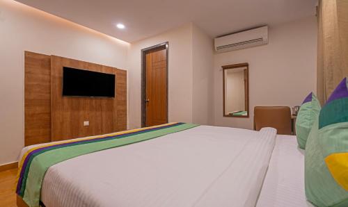a bedroom with a white bed and a television at Treebo SY Inn, Gachibowli DLF in Hyderabad