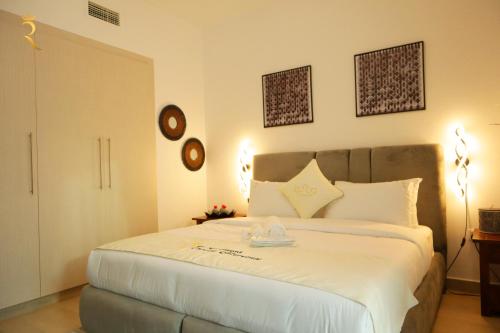 a bedroom with a large white bed with two clocks on the wall at Twilight 1BR apartment Yas Island in Abu Dhabi