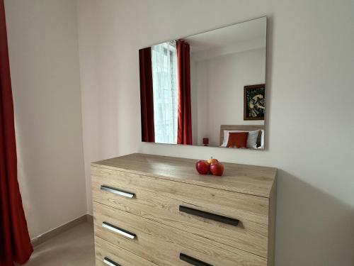 a dresser with a mirror and two apples on it at New, airy and spacious apartment in Mellieha in Mellieħa