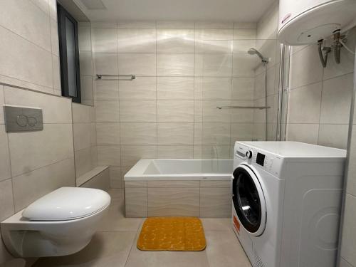 a bathroom with a toilet and a washing machine at New, airy and spacious apartment in Mellieha in Mellieħa