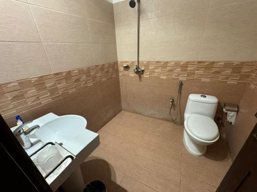 a bathroom with a white toilet and a sink at Shelton Boulevard Hotel Lahore in Lahore