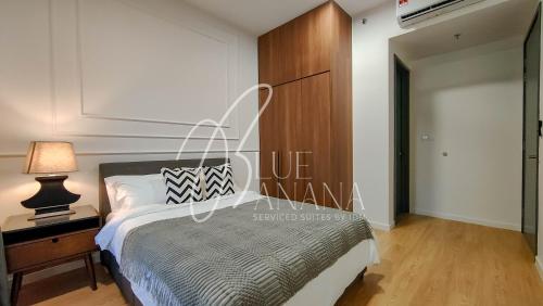 ein Schlafzimmer mit einem Bett und einem Nachttisch mit einer Lampe in der Unterkunft Inspirasi Mont Kiara Premier Suites by BlueBanana in Kuala Lumpur