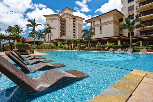 a swimming pool with lounge chairs in a resort at Ko Olina Beach Villas O1402 in Kapolei