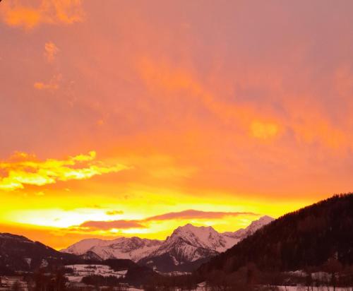 een zonsondergang in de bergen met besneeuwde bergen bij Haus Pyhrgasblick in Windischgarsten