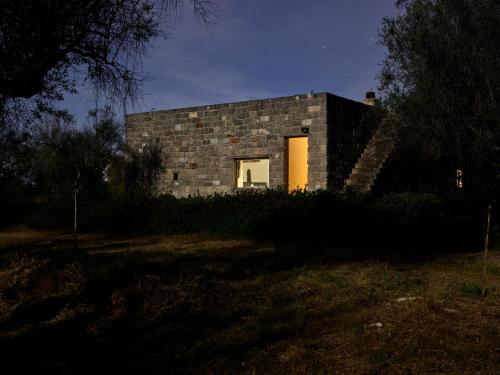 a stone house with a window in a field at Elegant modern Villa in olive grove in Surano