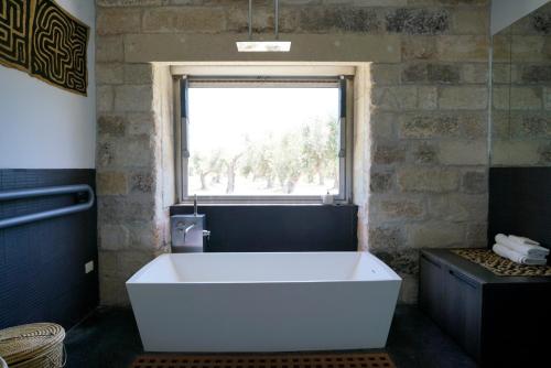 a large white tub in a bathroom with a window at Elegant modern Villa in olive grove in Surano