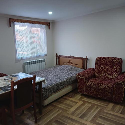 um quarto com uma cama, uma cadeira e uma mesa em Дом для гостей em Guiumri