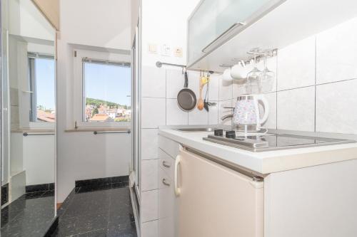 a white kitchen with a sink and a window at Rooms Gold in Split