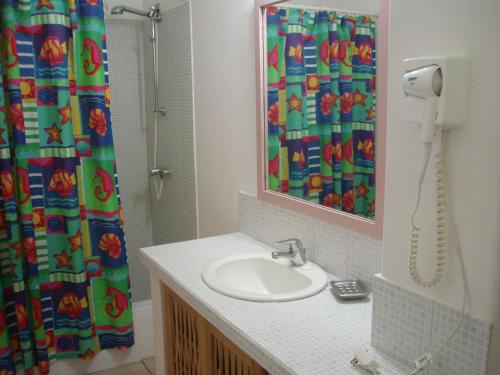 a bathroom with a sink and a shower curtain at The Nest Tobago Apartments in Buccoo