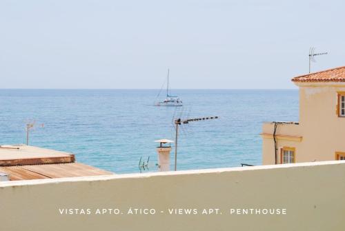 Apartamentos Vicenta Playa Carihuela في توريمولينوس: قارب في الماء خلف مبنى