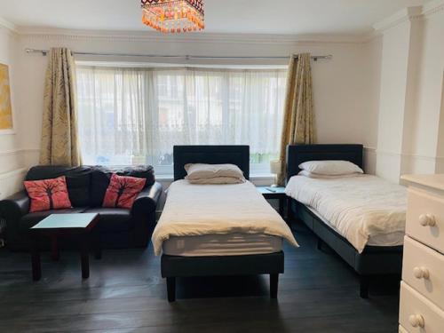 a bedroom with two beds and a couch and a chandelier at Circle Guest House Bed Only in Southampton