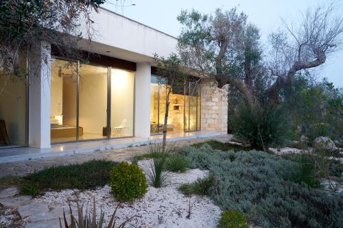 a house with large glass windows and a tree at Elegant modern Villa in olive grove in Surano