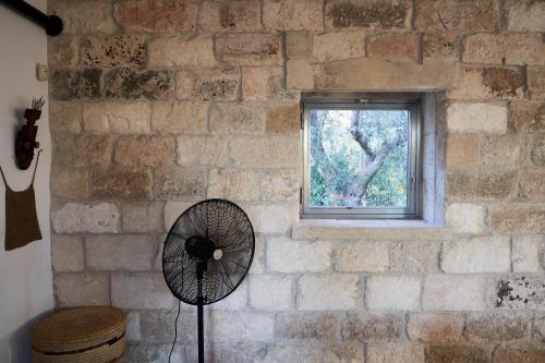 a brick wall with a fan in front of a window at Elegant modern Villa in olive grove in Surano