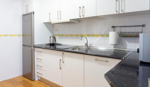 馬拉加的住宿－Elegant Malaga Retreat，厨房配有白色橱柜和不锈钢冰箱