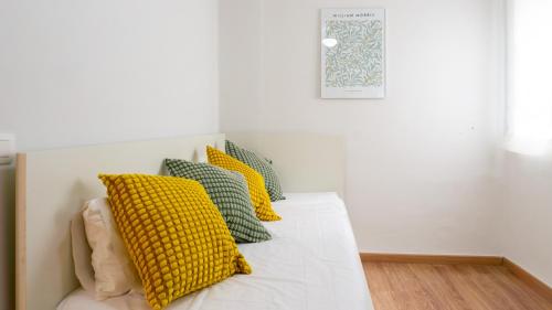 a white bed with yellow and green pillows on it at Elegant Malaga Retreat in Málaga