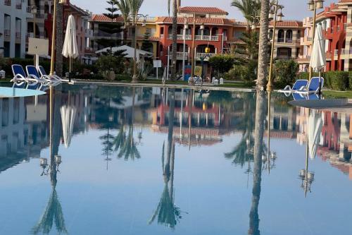 a pool at a resort with chairs and palm trees at Porto Matrouh unique Chalet in Marsa Matruh