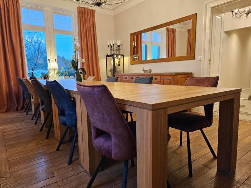 a dining room with a wooden table and chairs at L'ALBIZIA in Libin