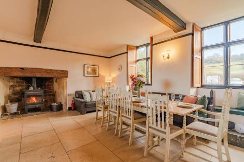 a dining room with a table and chairs and a fireplace at Canons Court Lodge in Wotton-under-Edge