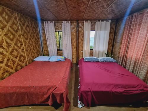 two beds in a room with a window at Shey's Travellers Inn in Mambajao