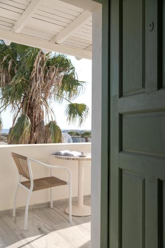 a table and chair on a porch with a palm tree at Ambeli Apartments in Perivolos