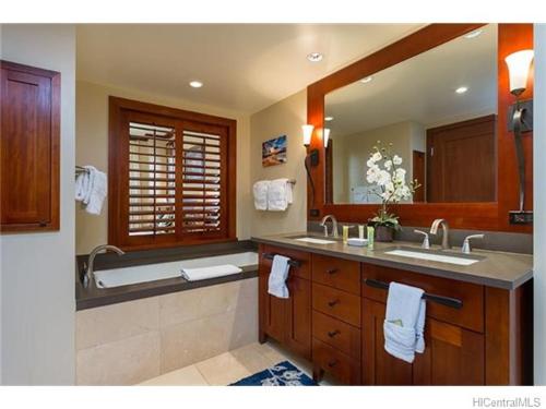 a bathroom with a sink and a tub and a mirror at Ko Olina Beach Villas O1406 in Kapolei