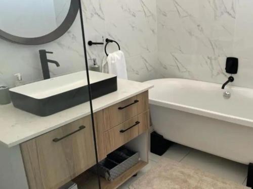 ein Badezimmer mit einem Waschbecken, einer Badewanne und einem Waschbecken in der Unterkunft Modern Executive Stay in Upington