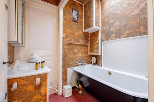 une salle de bain avec une baignoire et un lavabo dans l'établissement Veeve - Theatre in the Sky, à Paris