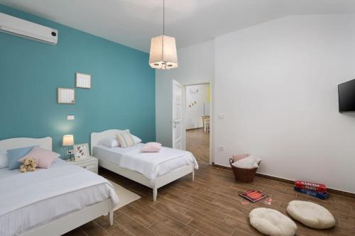 1 dormitorio con 2 camas y pared azul en Villa Limone by Istrialux, en Šivati